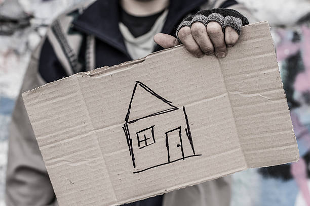Young homeless man holding sign with painted house